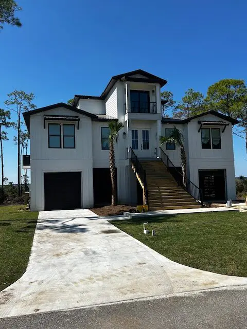 Modern two-story house with large windows and a spacious driveway.