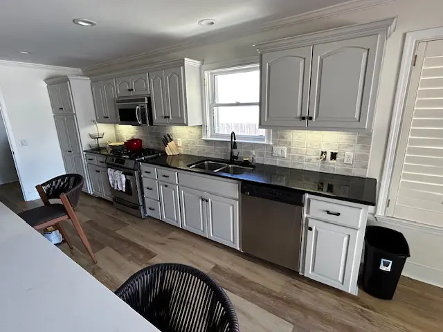 Modern kitchen with white cabinets and stainless steel appliances.