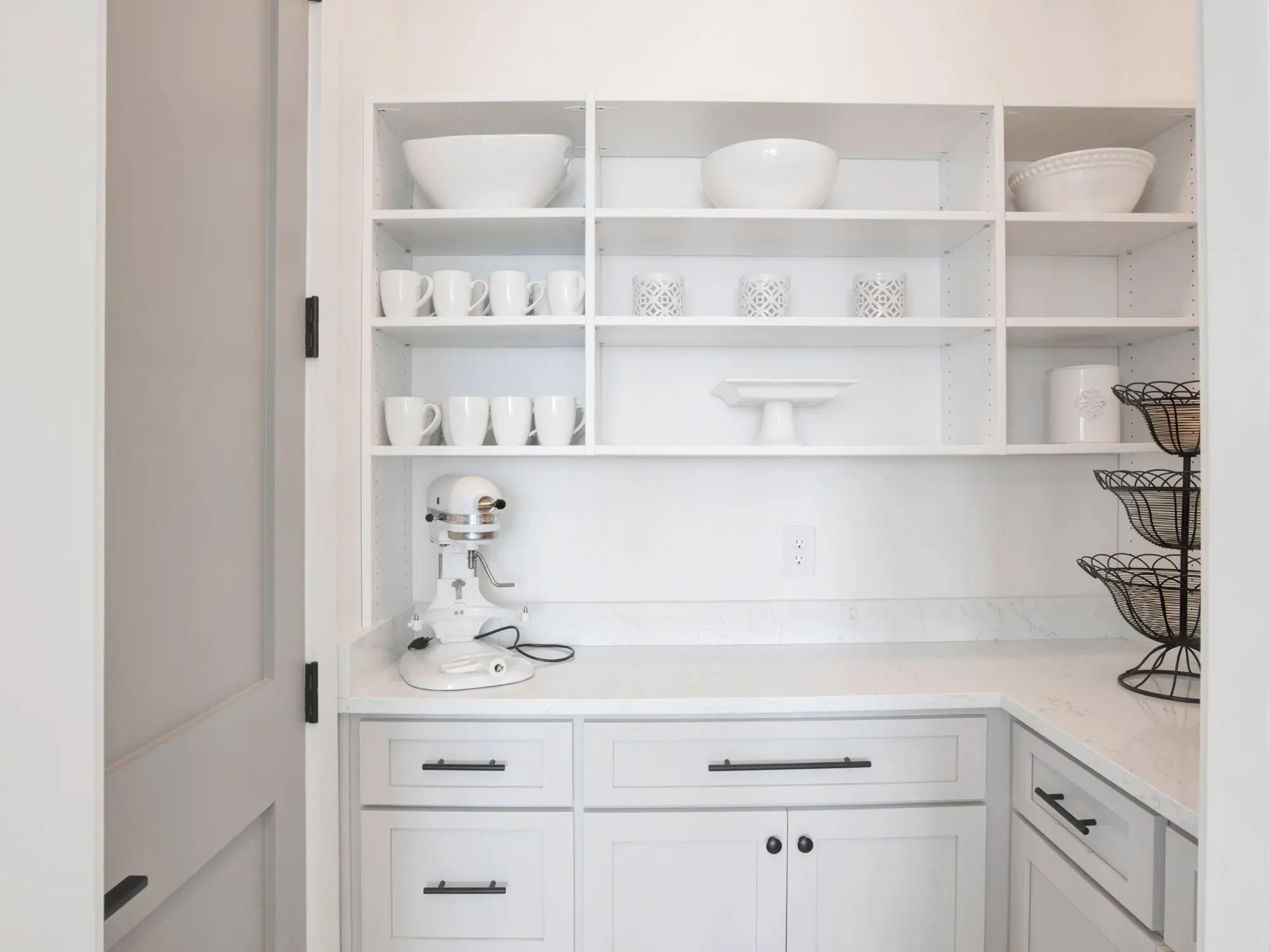 Minimalist white kitchen shelving with neatly arranged bowls and cups.
