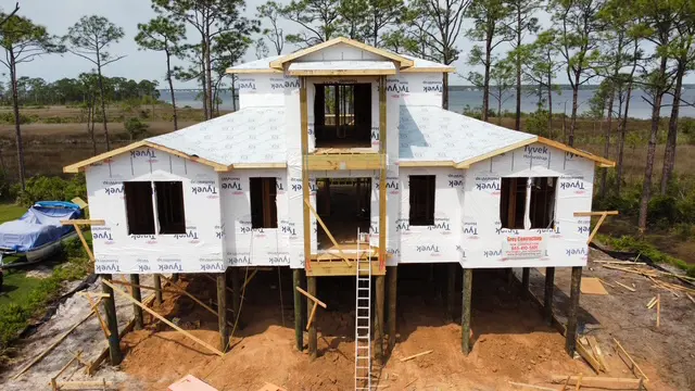 A house under construction with visible framing and wrap.