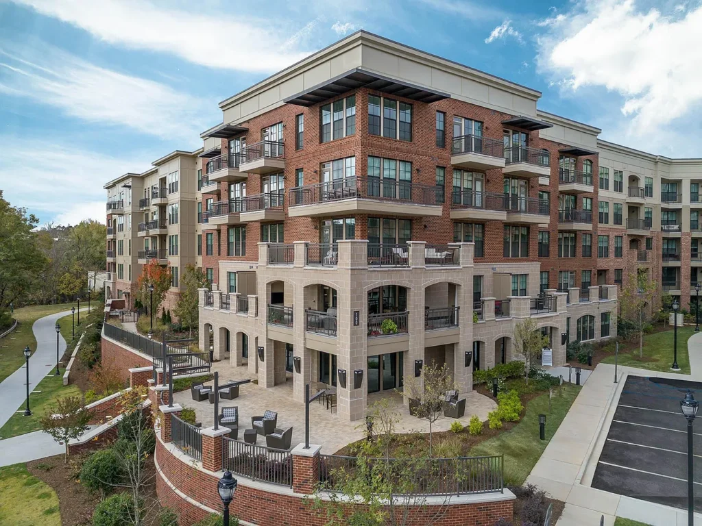 Modern multi-story residential building with balconies and outdoor seating areas.